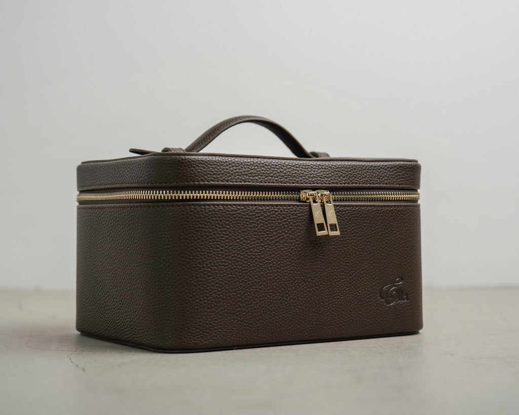 Brown leather cosmetic case with gold zipper on a light gray background