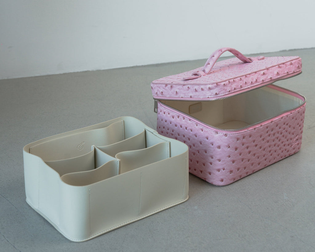 White rectangular organizer with compartments next to a pink textured box on a gray surface.