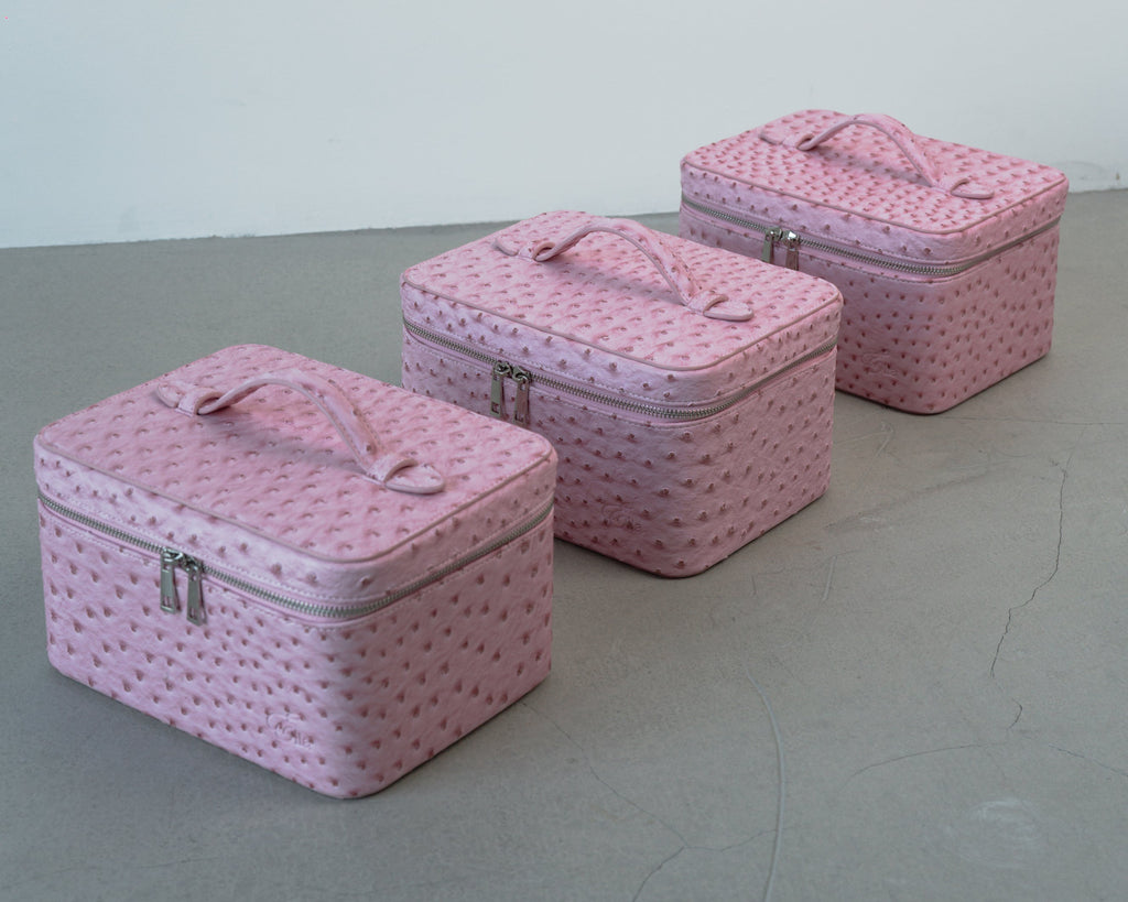 Set of three pink textured cosmetic cases on a gray surface with a white background